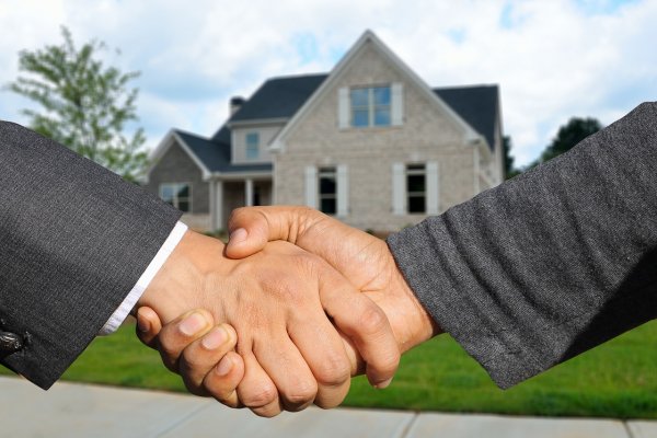 Shaking hands in front of a real estate sale